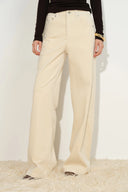 Cream wide leg pants with curved paneling and five pocket styling