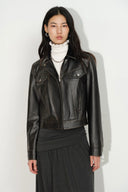 Woman wearing a fitted black vegan leather biker jacket with Western yoke seams and an asymmetrical zip