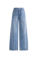 Light wash designer jeans with silver edged seams, whiskering, and wide straight legs