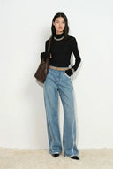 Model wearing light wash jeans with silver edged seams and a straight leg fit