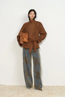 Model wearing floral flocked jacquard barrel jeans with a brown tie waist blouse and leather handbag