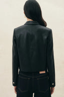 Back view of a black cropped vegan leather blazer with softly squared shoulders, shirt collar and cuff buttons