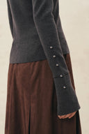 Charcoal stretch knit polo top with metallic buttons along the sleeve and flared cuffs