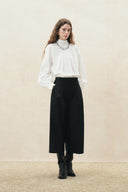 Model wearing black cropped wide leg wool blend pants with a high waist