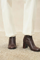 Ivory straight leg jeans with turned cuffs styled with dark brown heeled ankle boots