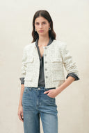 Model wearing a cropped cream shimmer check wool tweed jacket with welt pockets and dark trim