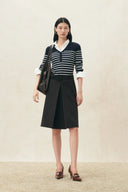 Model wearing a navy striped knit top with white collar and cuffs, black skirt, and shoulder bag