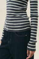 Gray and black striped ribbed knit top with long sleeves and dark denim jeans