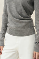 Gray knit polo top with gathered waist and long sleeves, styled with white trousers